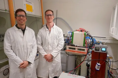 the two founders in the lab wearing lab coats and safety glasses